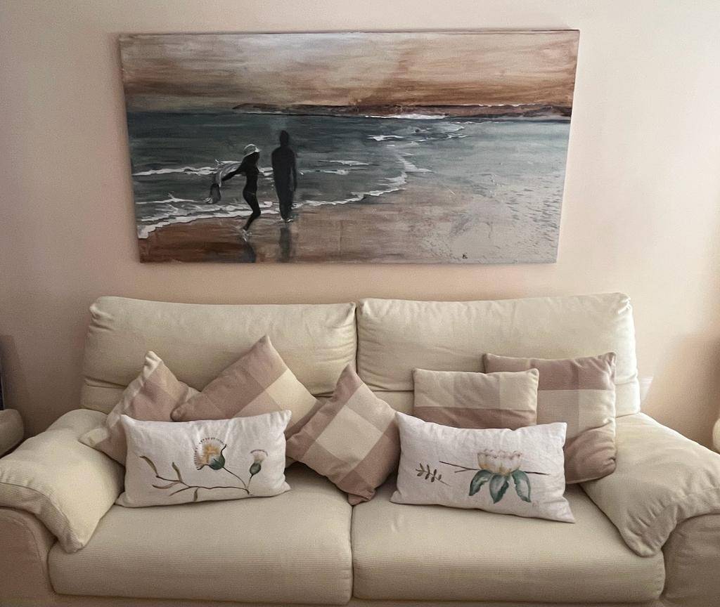 Cuadro artesanal con escena marina sobre un sofá beige, decoración natural en Algeciras.