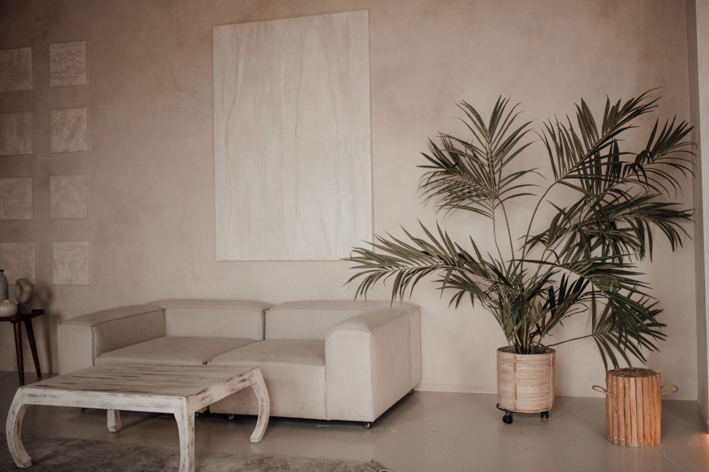 Salón decorado en tonos beige con sofá, planta natural y mesa artesanal, interiorismo en Algeciras.